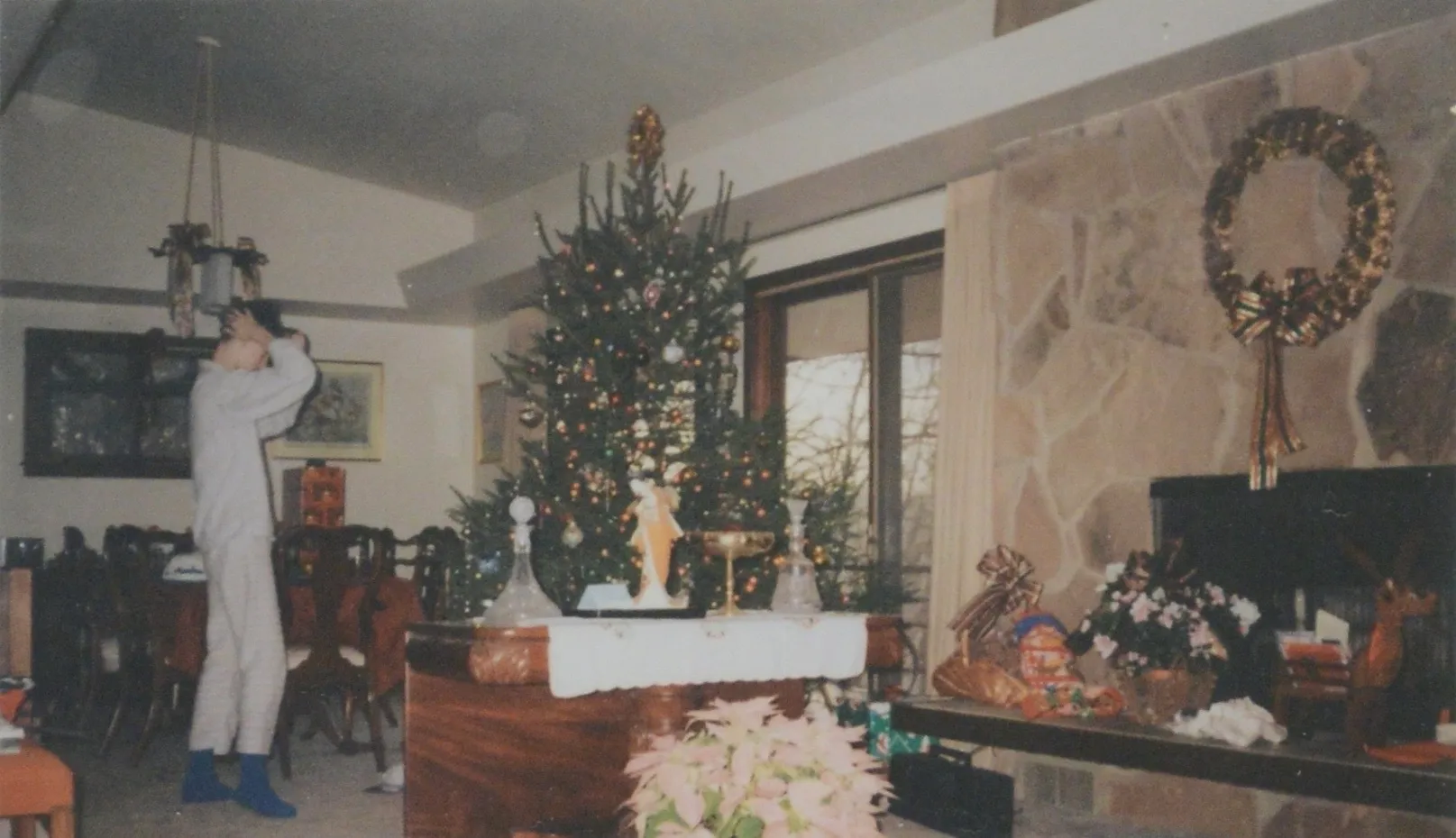Living and dining room decorated for Christmas, stone fireplace at right