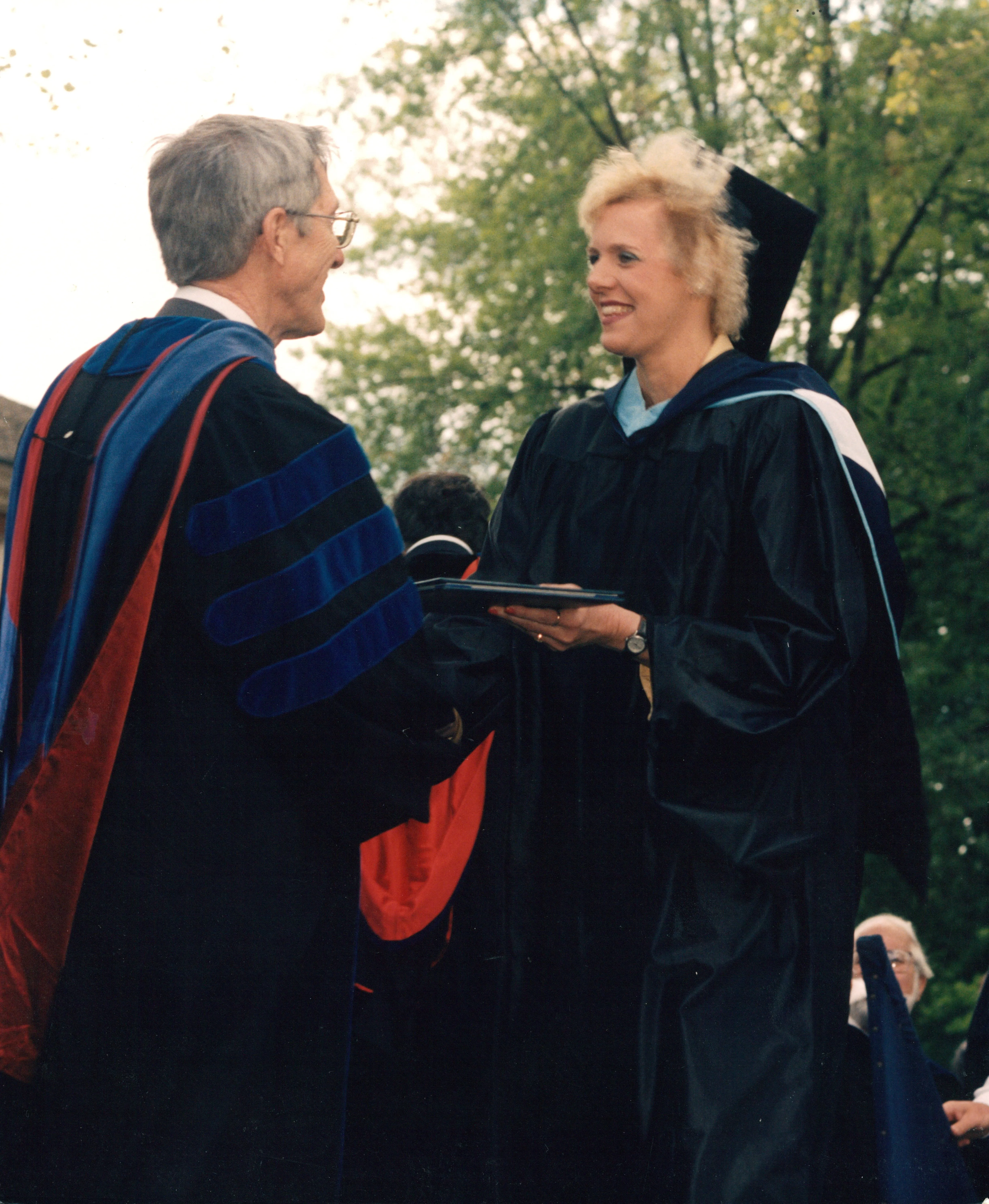 Terrie in mortarboard and graduation gown, receiving her diploma at the same ceremony.