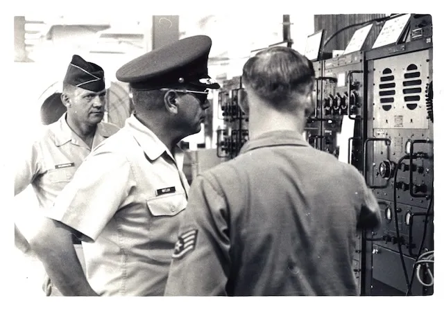 Officers inspecting communications equipment racks.