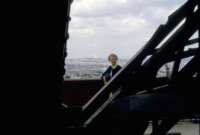 Peggy on the Eiffel Tower, Paris and Sacré-Cœur visible through the lattice.