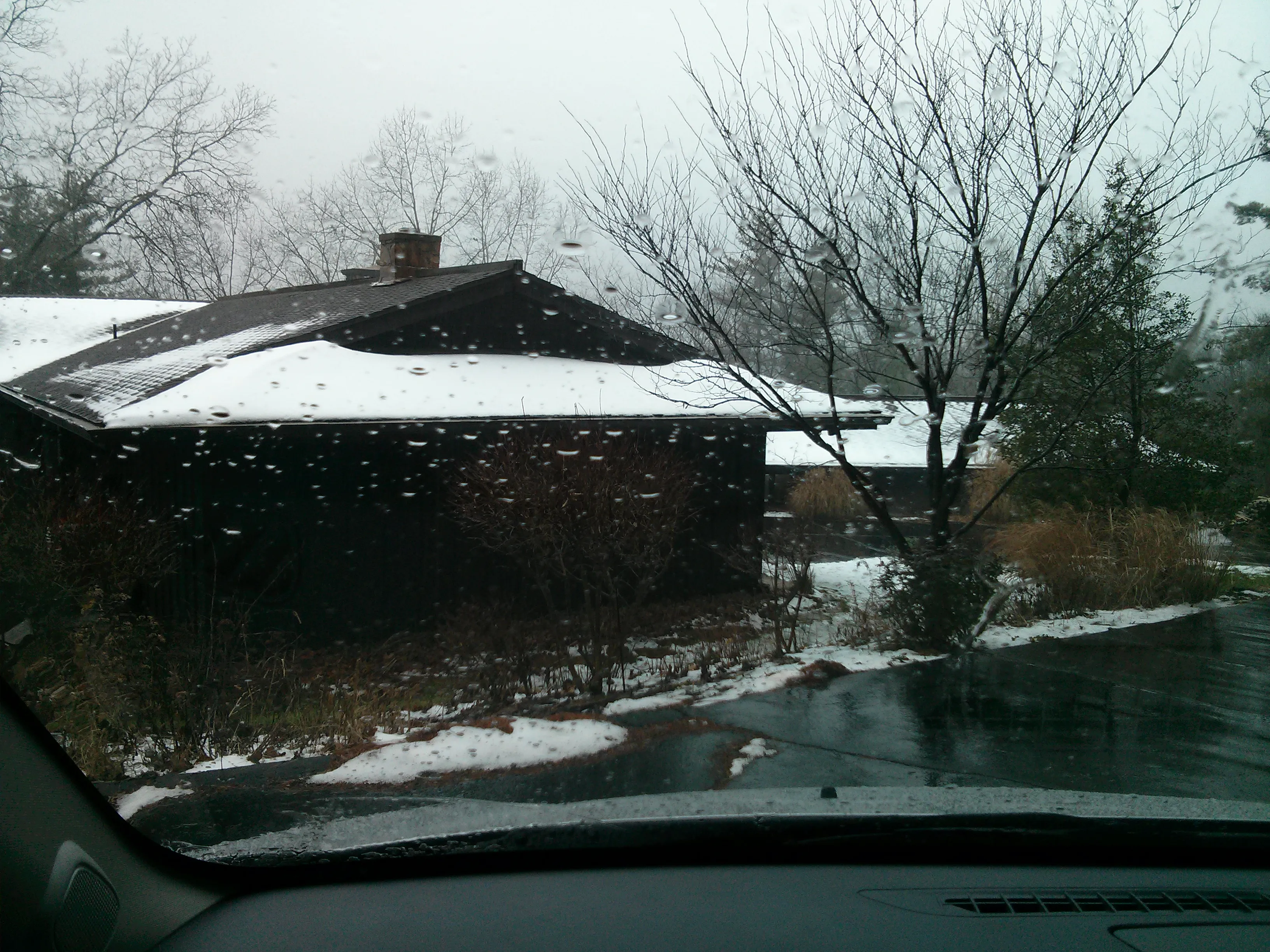 Exterior of the house seen through a rainy windshield, showing the low roof profile