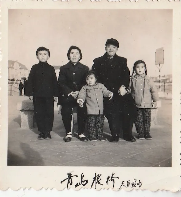 Lijie's maternal grandfather (right, in fur-collar coat) with Lijie's maternal grandmother and three of their children at the Qingdao Zhanqiao pier. The small boy on the left is Lijie's uncle Mengling Li; the two girls are his sisters, including (most plausibly) Lijie's mother. Photographed by Tianzhen Photography (天真照相) studio, c. 1960s. From Lijie's family's keeping.