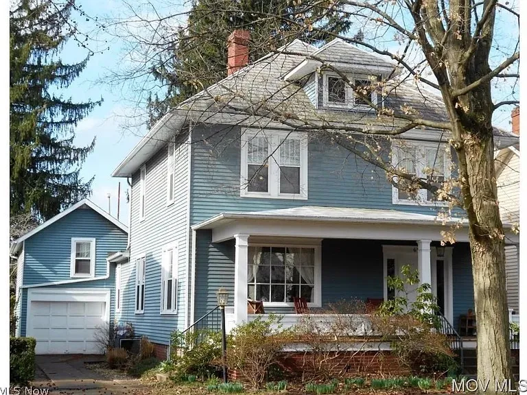 <strong>651 Sixth Street, Marietta — exterior and interior in a c. 2015–2020s real-estate listing.</strong> Three frames from a Mid-Ohio Valley MLS listing retrieved by Chuck Eesley 2026: the front of the house with '651' visible on the porch column; the side view showing the side entrance and garage; and the entryway with the staircase, hardwood floors, antique chest, grandfather clock, and piano. The architecture and renovation visible are consistent with the house Charlie's autobiography describes — an older two-story with a substantial front porch, the kind Will the architect would have bought to redesign around the family. The 1965 autobiography's 'playroom' completion would have been on the second floor; the staircase visible in the entryway is the same one his sisters Jeanne and Anne climbed from their old-upstairs-kitchen bedroom.