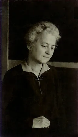 Alice Anderson McMaster in her schoolroom, undated — posed in front of the blackboard where she taught, her hair gone white, looking down. One of the quieter frames in the deck.