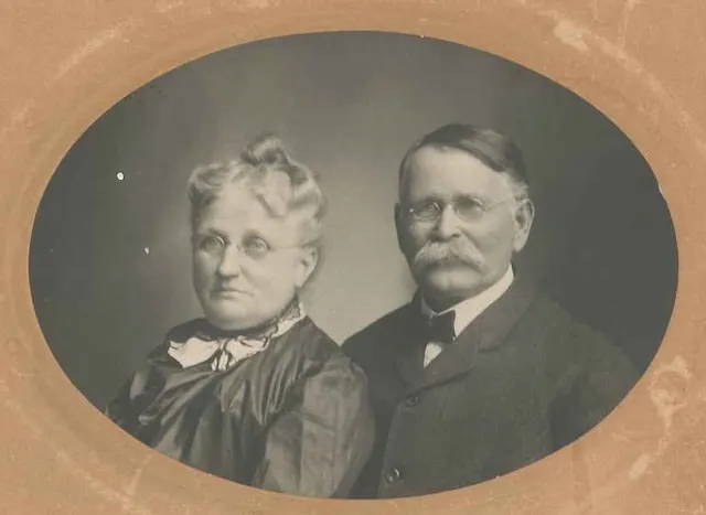 Oval studio portrait of Jacob and Elizabeth Wildermuth in later life, c. 1905–1911 — Elizabeth at left in a dark dress and lace collar, Jacob at right with wire-rimmed glasses and a white mustache.