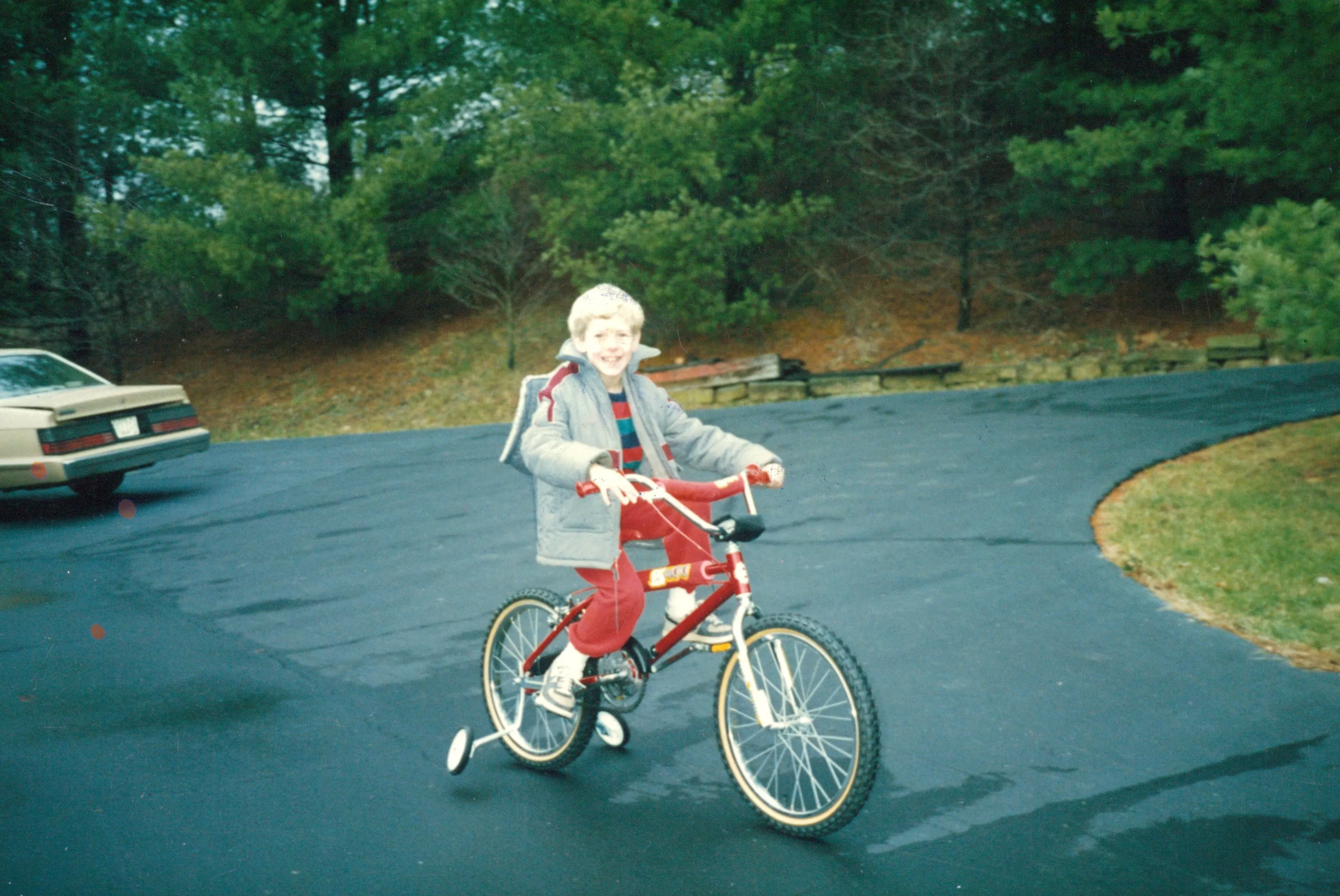 Young Chuck on a red bike on the Highland Ridge driveway, c. 1984–86