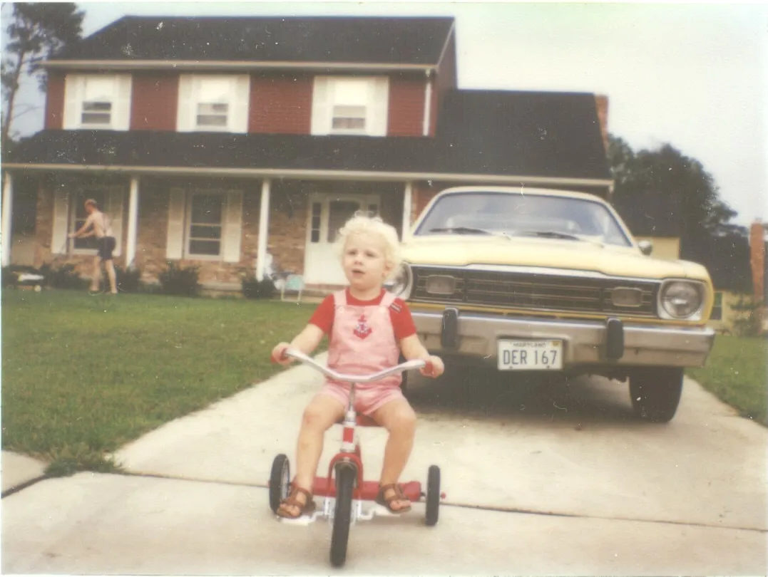 Young Chuck on a red tricycle — the Annapolis house, c. 1981–83