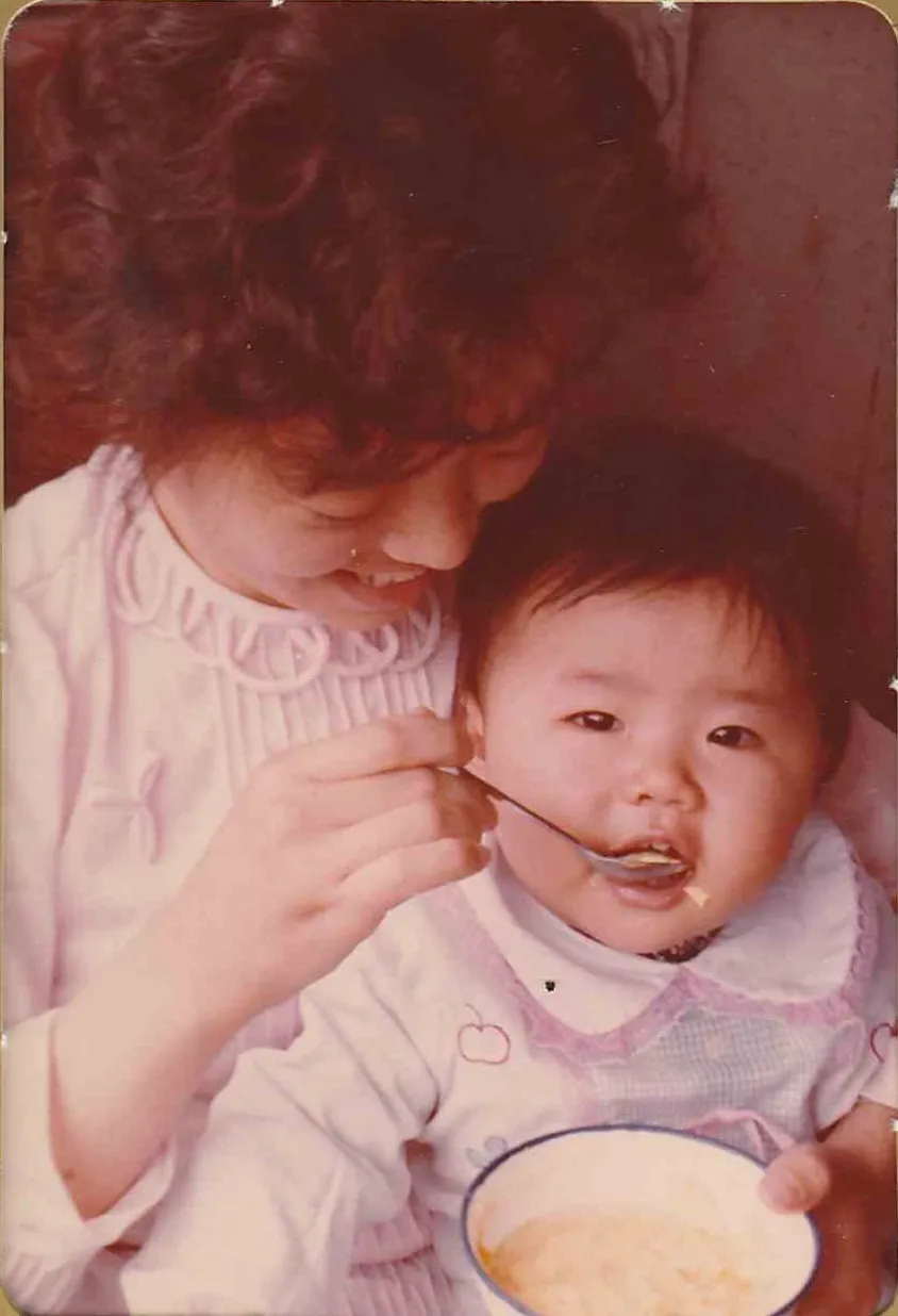A young woman spoon-feeding a baby, Qingdao, c. mid-1980s.